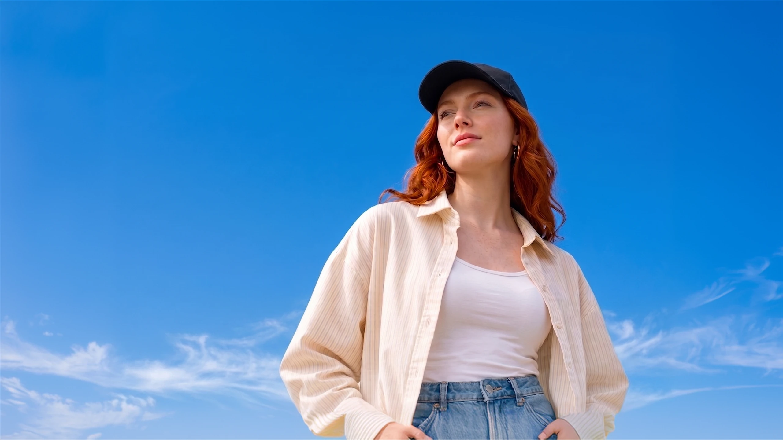Young woman standing against a bright blue sky